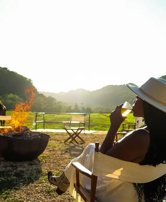 A guest enjoying a glass of wine by the campfire at The Stables at Sleeping Giant.