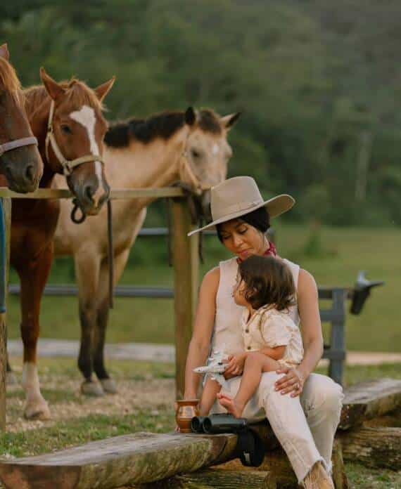 A mother and son sitting surrounded by horses at The Stables at Sleeping Giant.