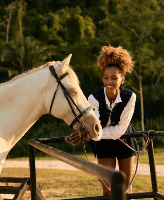 A guest gently petting a white horse at The Stables at Sleeping Giant in Belize.